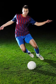 soccer player doing kick with ball on football stadium  field  isolated on black background  in night