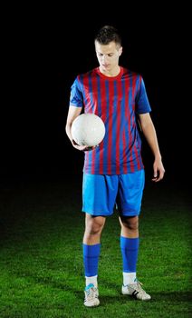 soccer player doing kick with ball on football stadium  field  isolated on black background  in night