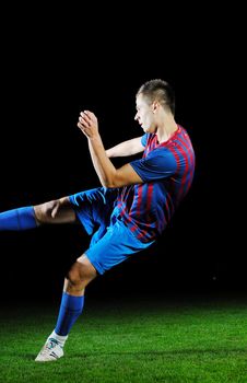 soccer player doing kick with ball on football stadium  field  isolated on black background  in night