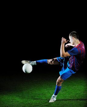 soccer player doing kick with ball on football stadium  field  isolated on black background  in night