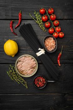 Uncooked Pasta with vegetables and tuna ingredients set, on black wooden table background, top view flat lay