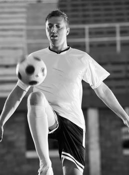 soccer player doing kick with ball on football stadium  field  isolated on black background  in night