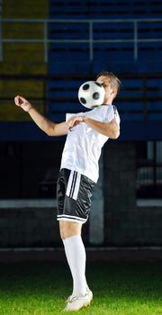 soccer player doing kick with ball on football stadium  field  isolated on black background  in night