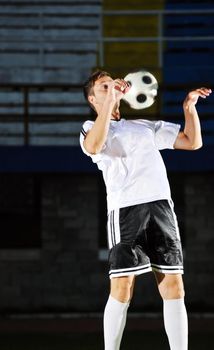 soccer player doing kick with ball on football stadium  field  isolated on black background  in night