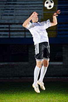 soccer player doing kick with ball on football stadium  field  isolated on black background  in night