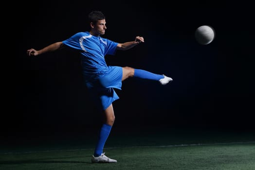 soccer player doing kick with ball on football stadium  field  isolated on black background