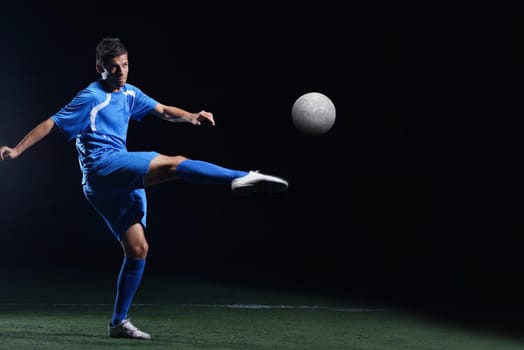 soccer player doing kick with ball on football stadium  field  isolated on black background