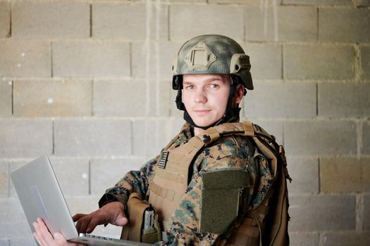 American soldier in military uniform using laptop computer for drone controlling and to stay in contact with friends and family