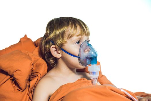 Boy making inhalation with a nebulizer at home.