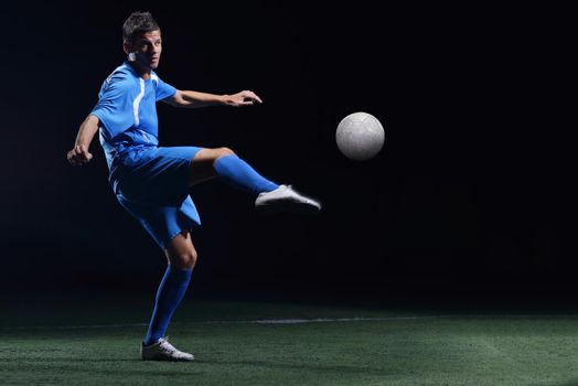 soccer player doing kick with ball on football stadium  field  isolated on black background