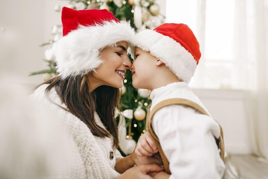 Portrait of happy mother and her son celebrate Christmas in festively decorated room , close up