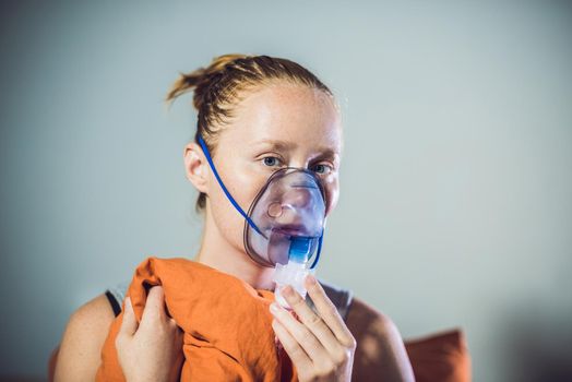 Woman with flu or cold symptoms making inhalation with nebulizer - medical inhalation therapy.