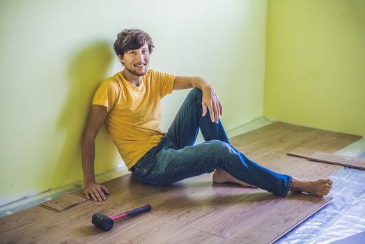 Man installing new wooden laminate flooring on a warm film floor. infrared floor heating system under laminate floor