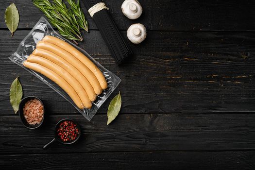 Sausages vacuum packed set, on black wooden table background, top view flat lay, with copy space for text
