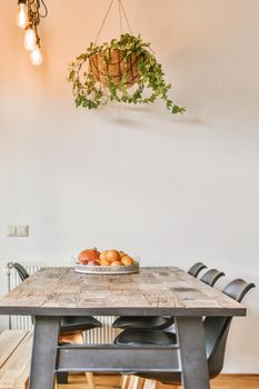 Stylish home interior design of dining zone with lamps hanging over wooden table and chairs in modern apartment with minimalist design