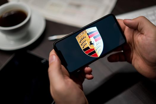 New York, New York / USA - 11 11 2019: Logo of Porsche on the iPhone X in hands in office