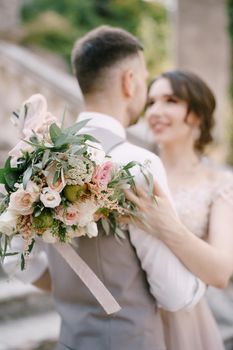 Bride with a bouquet hugs groom on the stone steps. Portrait. High quality photo