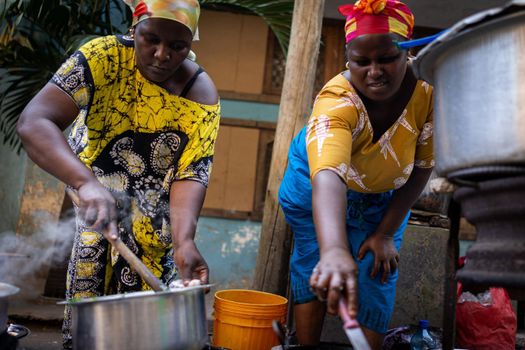 African woman cooking traditional food at street