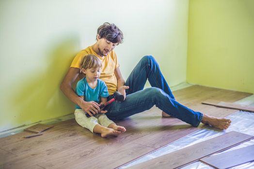 Father and son installing new wooden laminate flooring on a warm film floor. infrared floor heating system under laminate floor