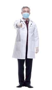 in full growth. a strict doctor in a protective mask pointing at you. isolated on a white background.