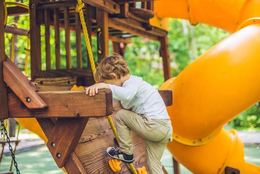 Cute little boy is playing on a wooden playground.