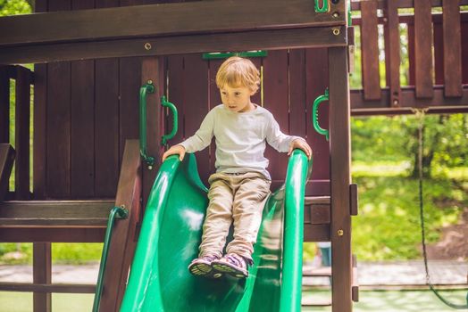 Cute little boy is playing on a wooden playground.