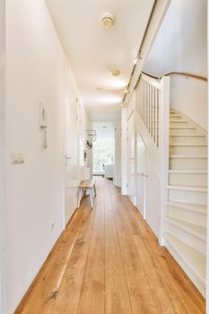 Interior of the narrow corridor with telephone hanging on the wall against stairway in daylight