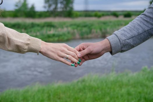 Hands of man and woman reaching to each other. Soft, gentle touch of hands on background of nature. Be hand in hand. Concept of Love, connection, help, relation, community, togetherness, symbolism.