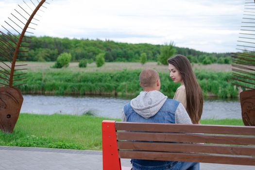 beautiful young couple sitting on a bench in the park.