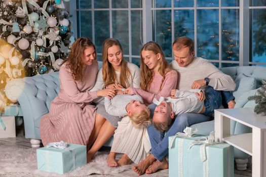 Big Happy family with many kids having fun on the sofa near the Christmas tree. Christmas family eve, christmas mood concept