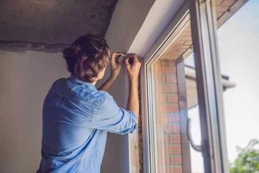 Man in a blue shirt does window installation.