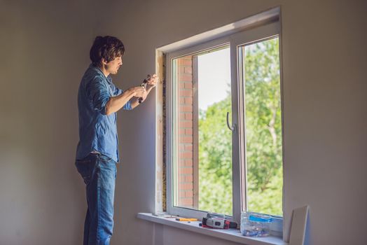 Man in a blue shirt does window installation.