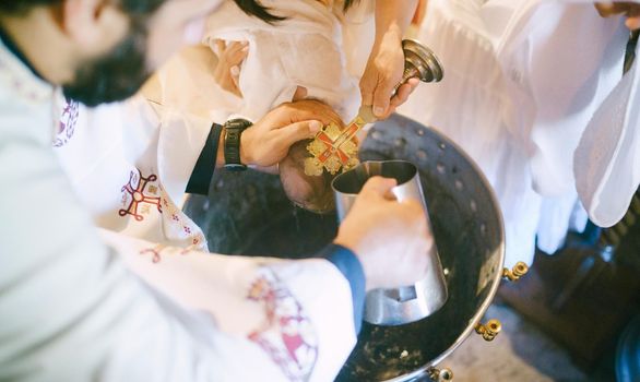 Priest washes the baby head from a jug during baptism over a basin. High quality photo