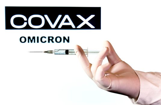 Madrid, Spain- November 29, 2021: Hand holding Syringe with covid-19 vaccine and Covax logo and Omicron variant word written on white background.