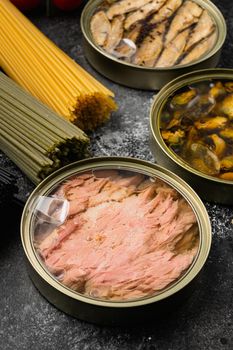 Cans of preserves with tuna, sprat and mussels set, on black dark stone table background