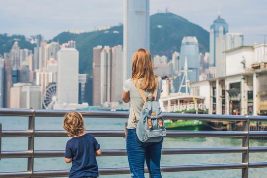 Young woman and her son taking photos of victoria harbor in Hong Kong, China.