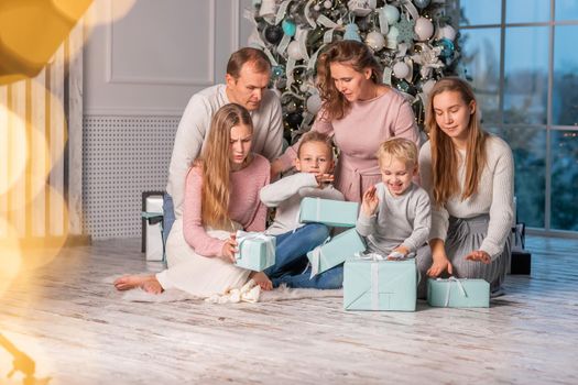 Big Happy family with many kids having fun and opening presents under the Christmas tree. Christmas family eve, christmas mood concept