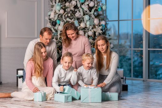 Big Happy family with many kids having fun and opening presents under the Christmas tree. Christmas family eve, christmas mood concept