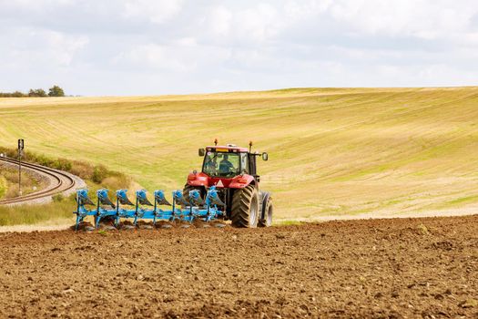 Farmer in red tractor preparing land for sowing