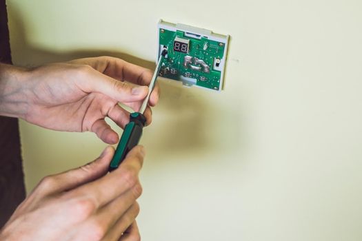 electrician installing an electrical thermostat in a new house.