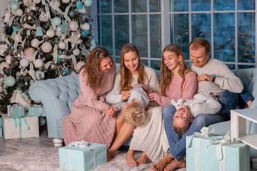 Big Happy family with many kids having fun on the sofa near the Christmas tree. Christmas family eve, christmas mood concept