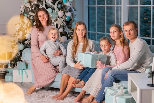 Big Happy family with many kids having fun on the sofa near the Christmas tree. Christmas family eve, christmas mood concept