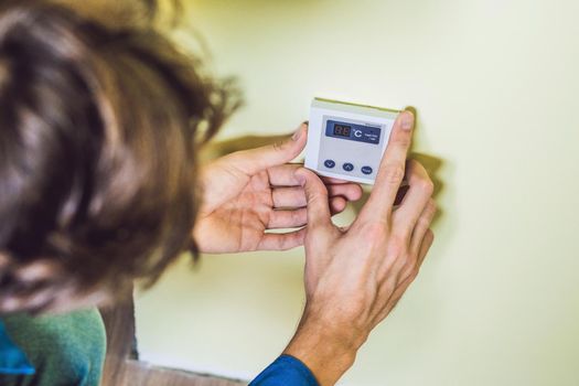 electrician installing an electrical thermostat in a new house.