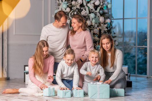 Big Happy family with many kids having fun and opening presents under the Christmas tree. Christmas family eve, christmas mood concept