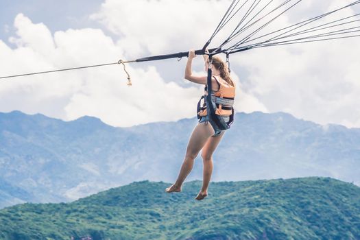 Young woman flies on a parachute among the clouds.