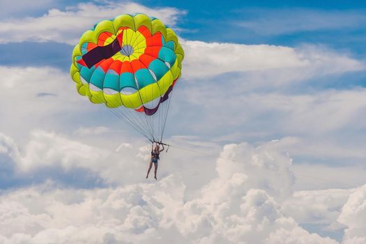 Young woman flies on a parachute among the clouds.