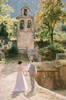 Groom and bride go to a small chapel in the garden of an old villa. High quality photo