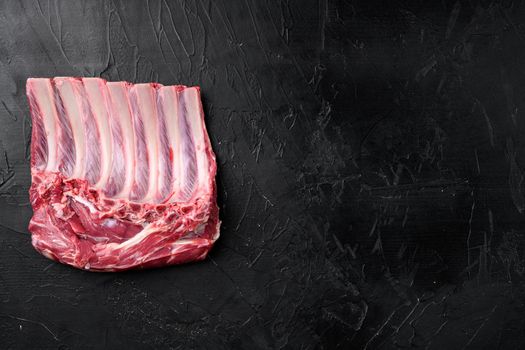 Raw fresh rack of lamb meat set, on black dark stone table background, top view flat lay, with copy space for text