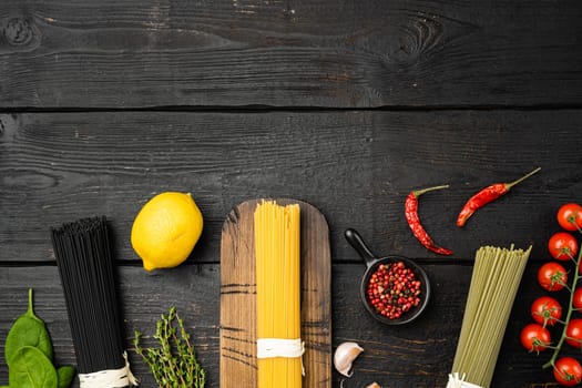 Multi colored spaghetti with ingredients set, on black wooden table background, top view flat lay, with copy space for text