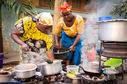 African woman cooking traditional food at street